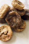 Figs... but dried. Dried figs look like mushrooms. There is a messy small pile of figs on a white marble bench-top.