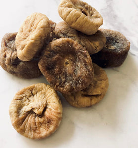 Figs... but dried. Dried figs look like mushrooms. There is a messy small pile of figs on a white marble bench-top.