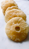 Pineapple slices that look dusty and rigid placed down like dominoes on white baking paper.