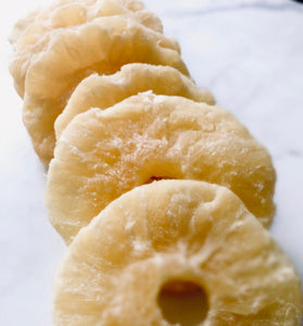 Pineapple slices that look dusty and rigid placed down like dominoes on white baking paper.