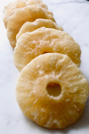 Pineapple slices that look dusty and rigid placed down like dominoes on white baking paper.