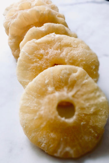 Pineapple slices that look dusty and rigid placed down like dominoes on white baking paper.