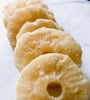 Pineapple slices that look dusty and rigid placed down like dominoes on white baking paper.