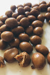 A short strip of chocolate coated sutltanas fill the image down the middle top to bottom. One is broken to demonstrate there are sultanas inside.