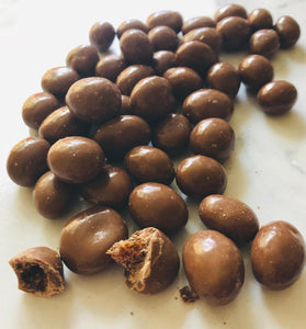 A short strip of chocolate coated sutltanas fill the image down the middle top to bottom. One is broken to demonstrate there are sultanas inside.
