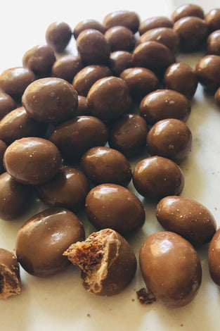 A short strip of chocolate coated sutltanas fill the image down the middle top to bottom. One is broken to demonstrate there are sultanas inside.