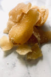 A few chunks of sweetened ginger are in the centre of the image. It is on a white marble background.