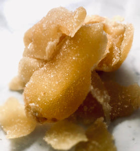 A few chunks of sweetened ginger are in the centre of the image. It is on a white marble background.