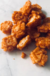 A handful of chili rice crackers in a pile on a white marble table.