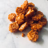 A handful of chili rice crackers in a pile on a white marble table.