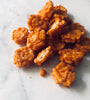 A handful of chili rice crackers in a pile on a white marble table.