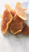 4 chunks of orange preserved mango on a white marble  bench-top.