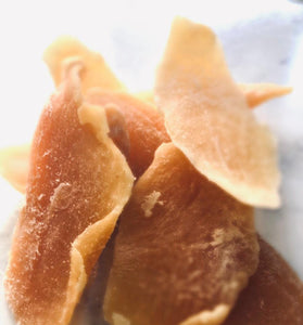 4 chunks of orange preserved mango on a white marble  bench-top.