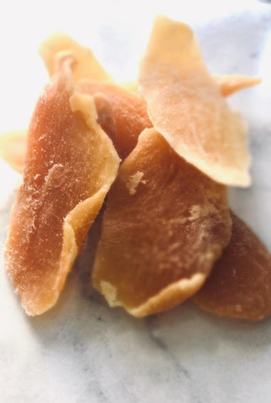 4 chunks of orange preserved mango on a white marble  bench-top.