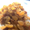 Bright yellow and brown sultanas that sparkle in the light. A large handful takes up most of the image. 
