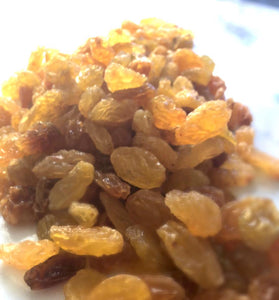 Bright yellow and brown sultanas that sparkle in the light. A large handful takes up most of the image. 