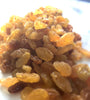 Bright yellow and brown sultanas that sparkle in the light. A large handful takes up most of the image. 
