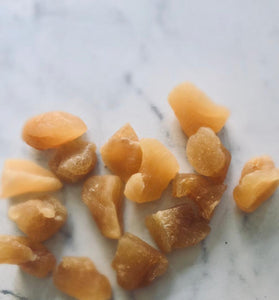 Delicious ginger chunks. They make me so hungry. I waaaant them nowww. A handful are near each other on a white marble table.