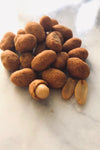 Flour coated peanuts with chili flavoring in a small round pile on a white marble table.