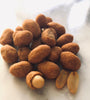 Flour coated peanuts with chili flavoring in a small round pile on a white marble table.