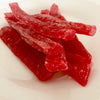 Dark red strips of paw paw piled in the middle of a white plate.