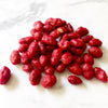 Dark red colored nuts on a white marble table.