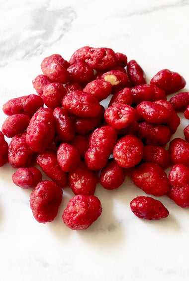 Dark red colored nuts on a white marble table.