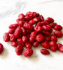 Dark red colored nuts on a white marble table.